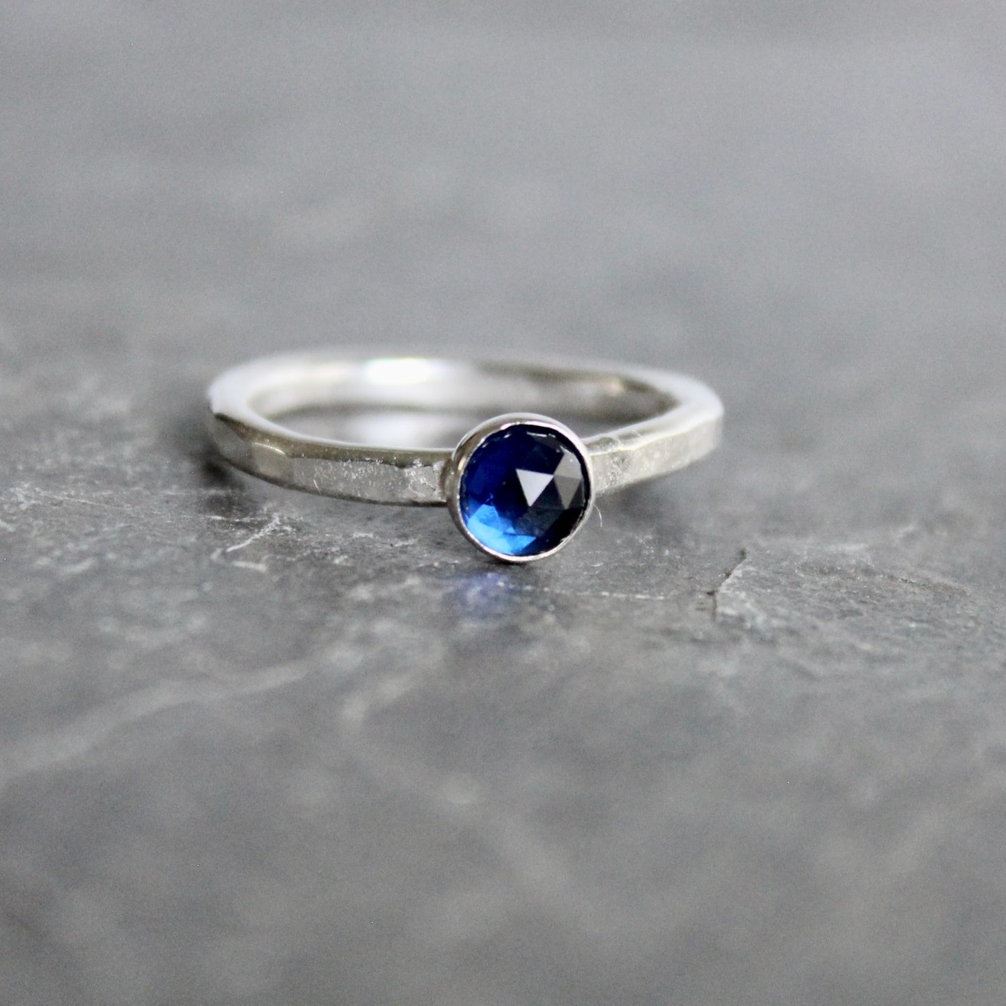 Silver ring with a blue gemstone on a gray surface