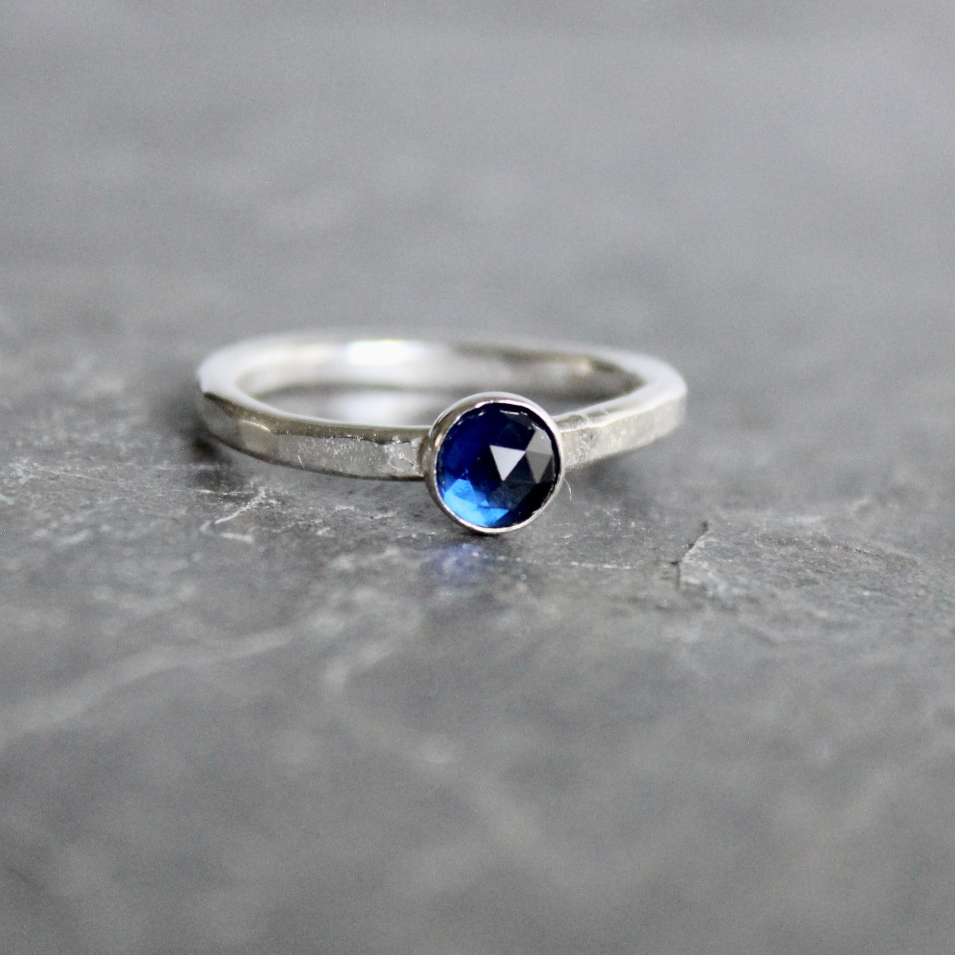 Silver ring with a blue gemstone on a gray surface