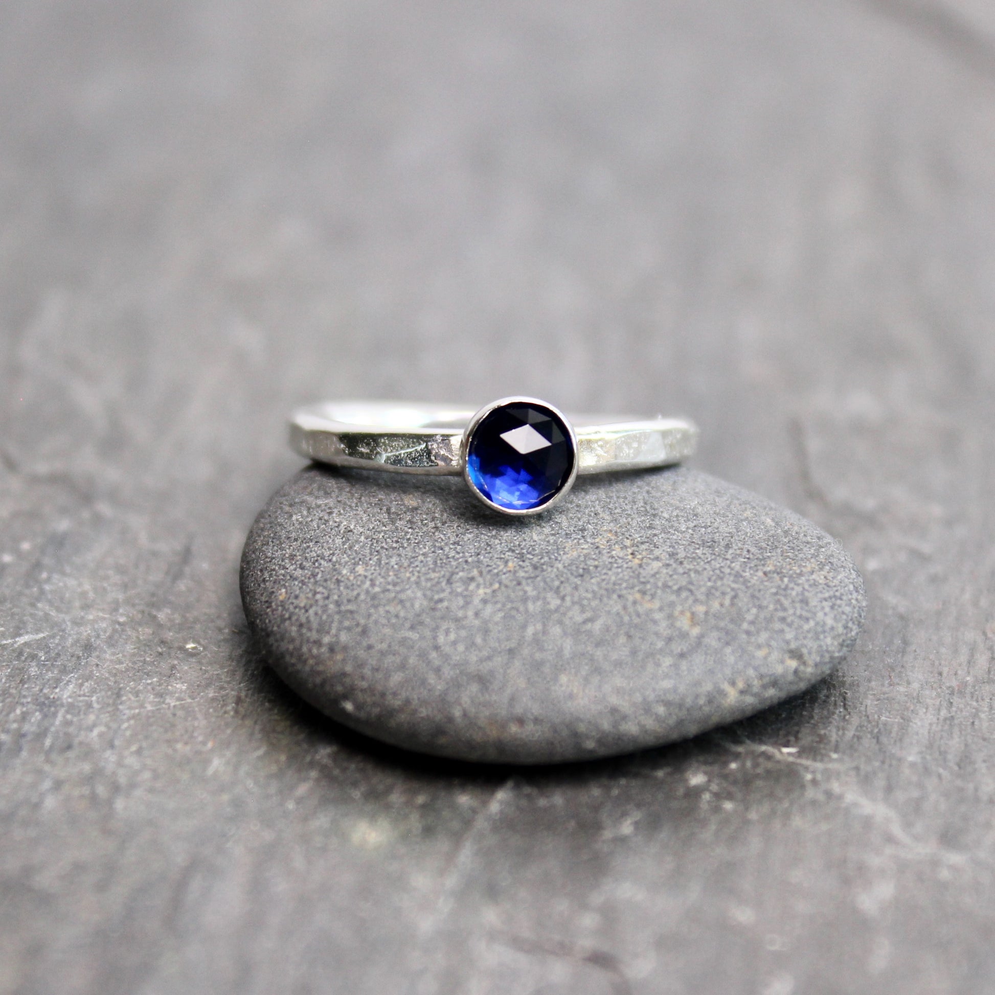 Silver ring with a blue gemstone on a gray stone surface