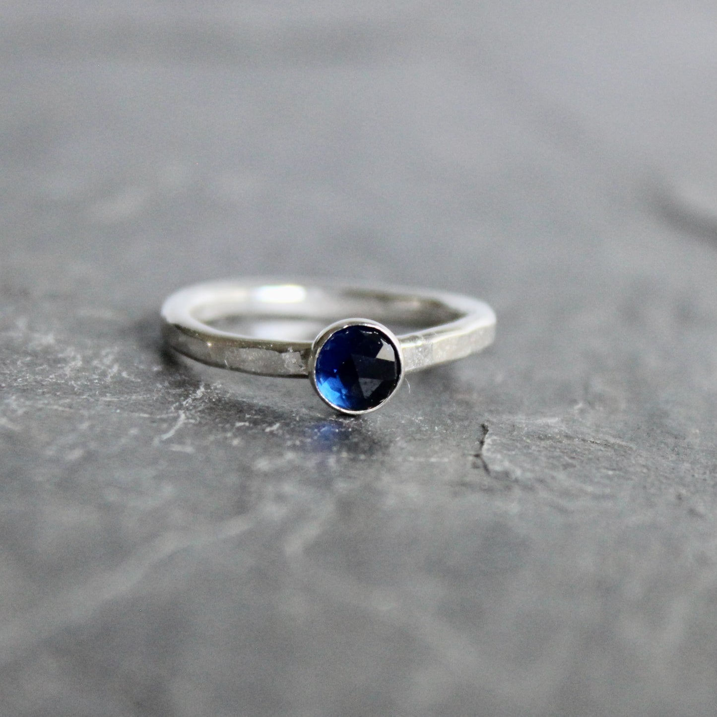 Silver ring with a blue gemstone on a gray surface