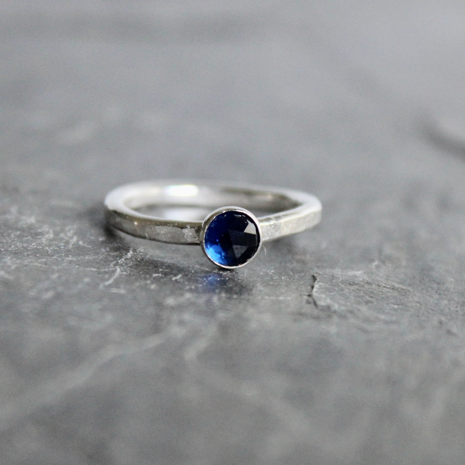 Silver ring with a blue gemstone on a gray surface