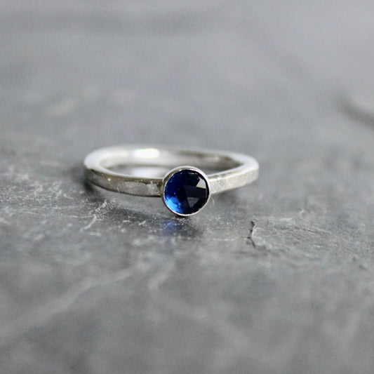 Silver ring with a blue gemstone on a gray surface
