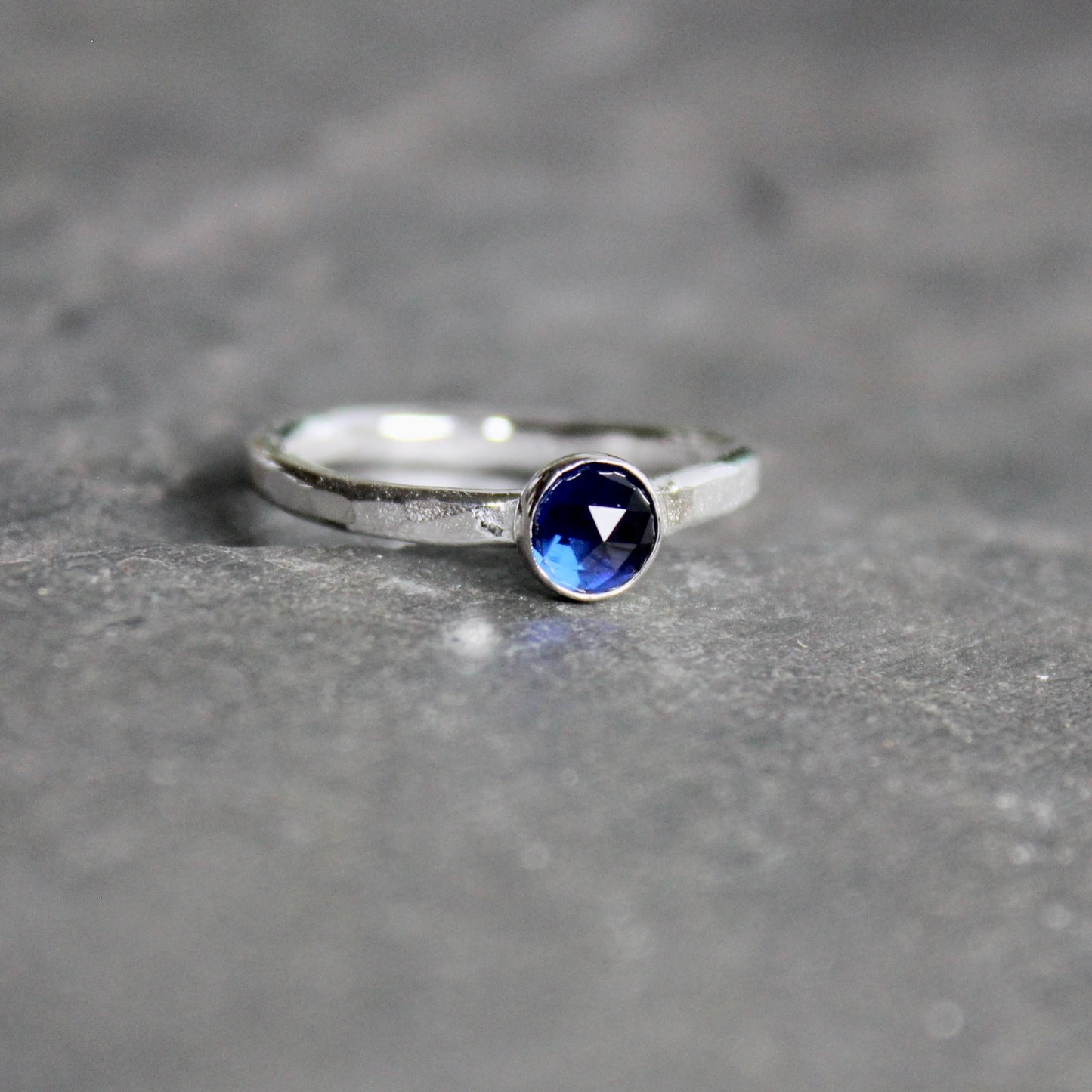Silver ring with a blue gemstone on a gray surface