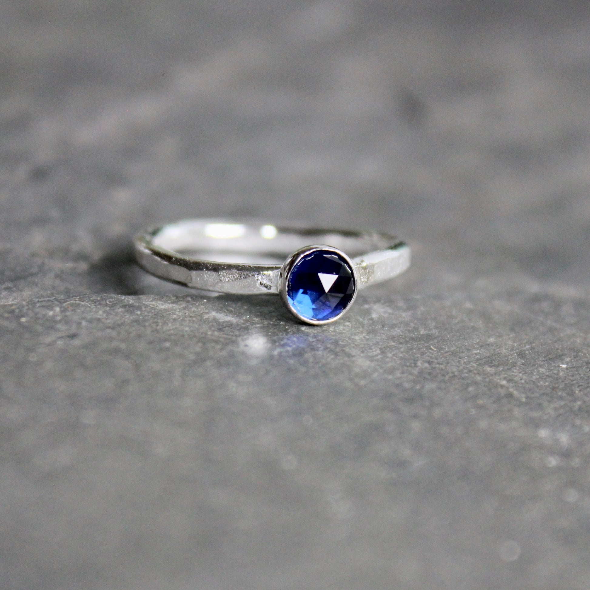 Silver ring with a blue gemstone on a gray surface