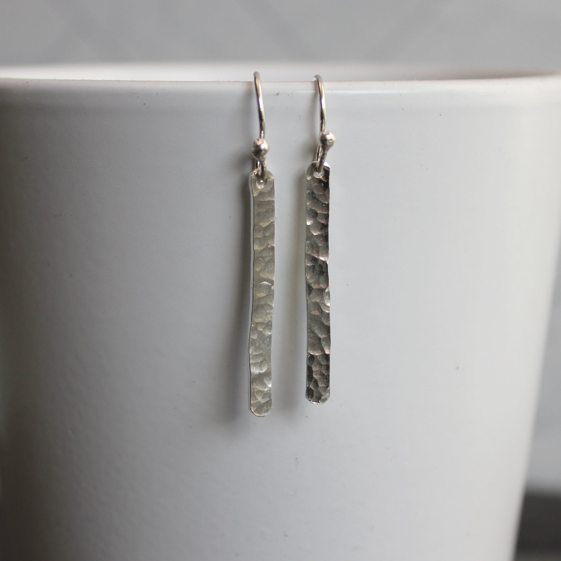 Silver textured earrings on a white surface