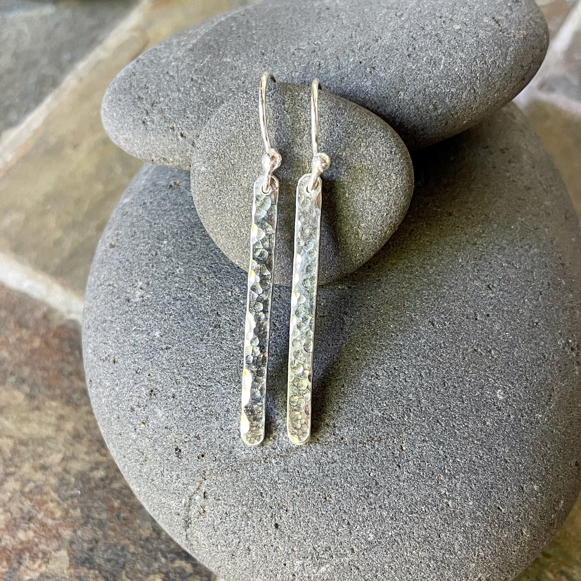 Silver bar earrings on a stack of gray stones