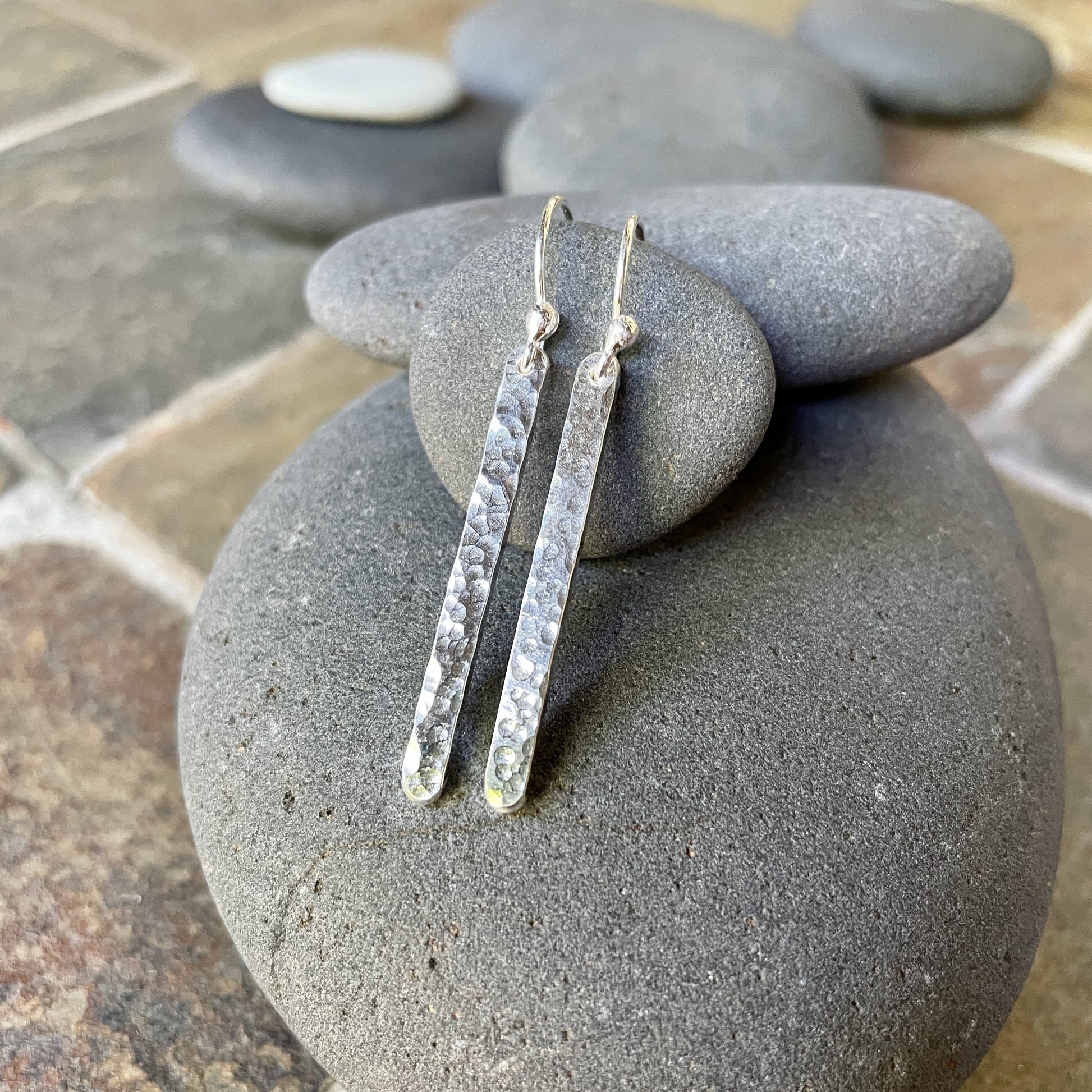 Silver earrings on a stack of gray stones