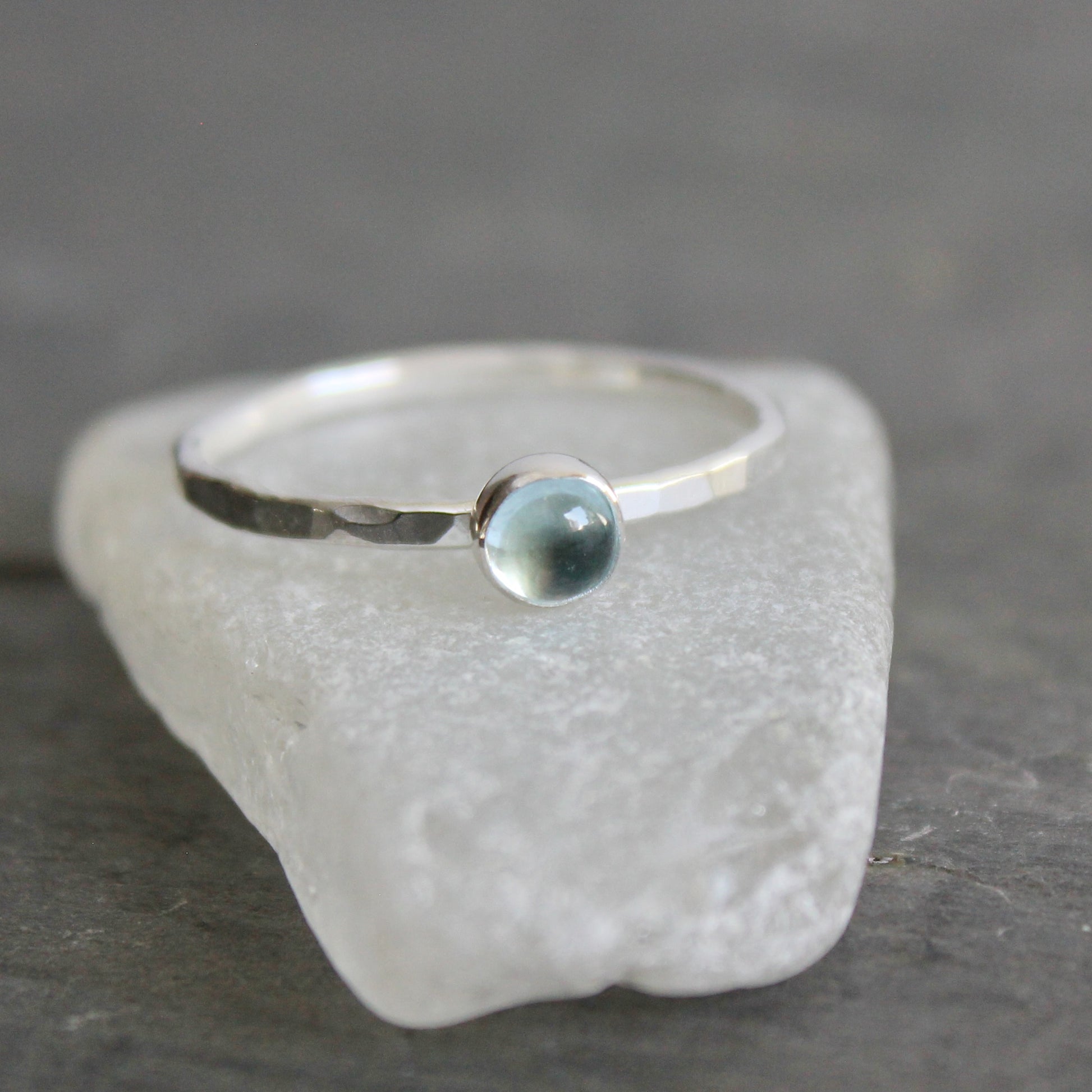Silver ring with a sky blue topaz on a textured stone surface