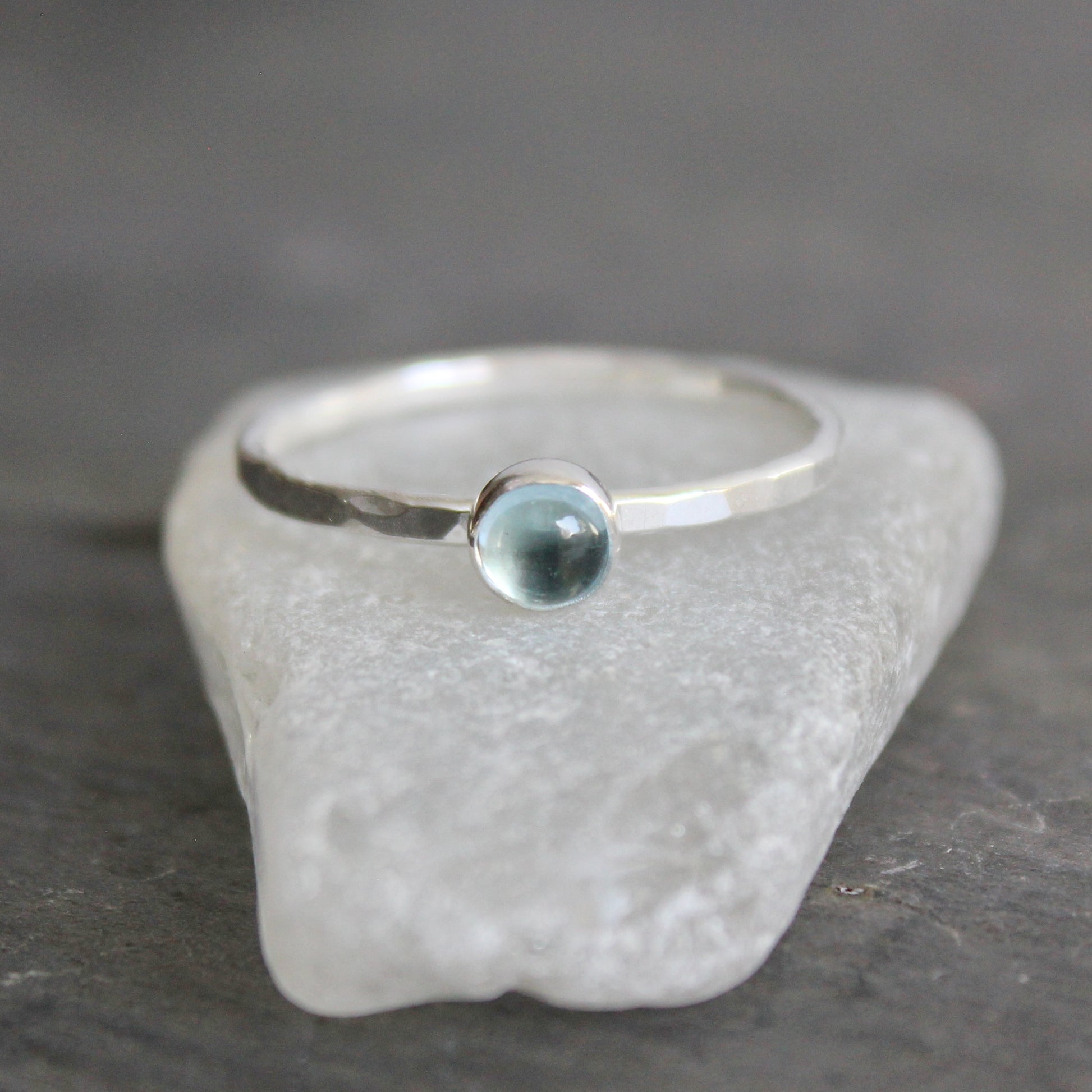 Silver ring with a sky blue topaz ring on a textured stone surface