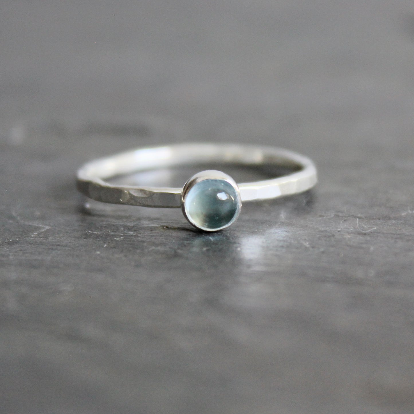 Silver ring with a blue topaz on a gray background