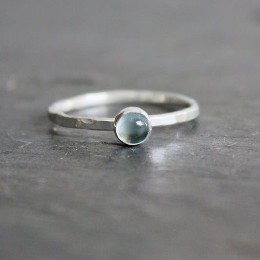 Silver ring with a blue topaz on a gray background