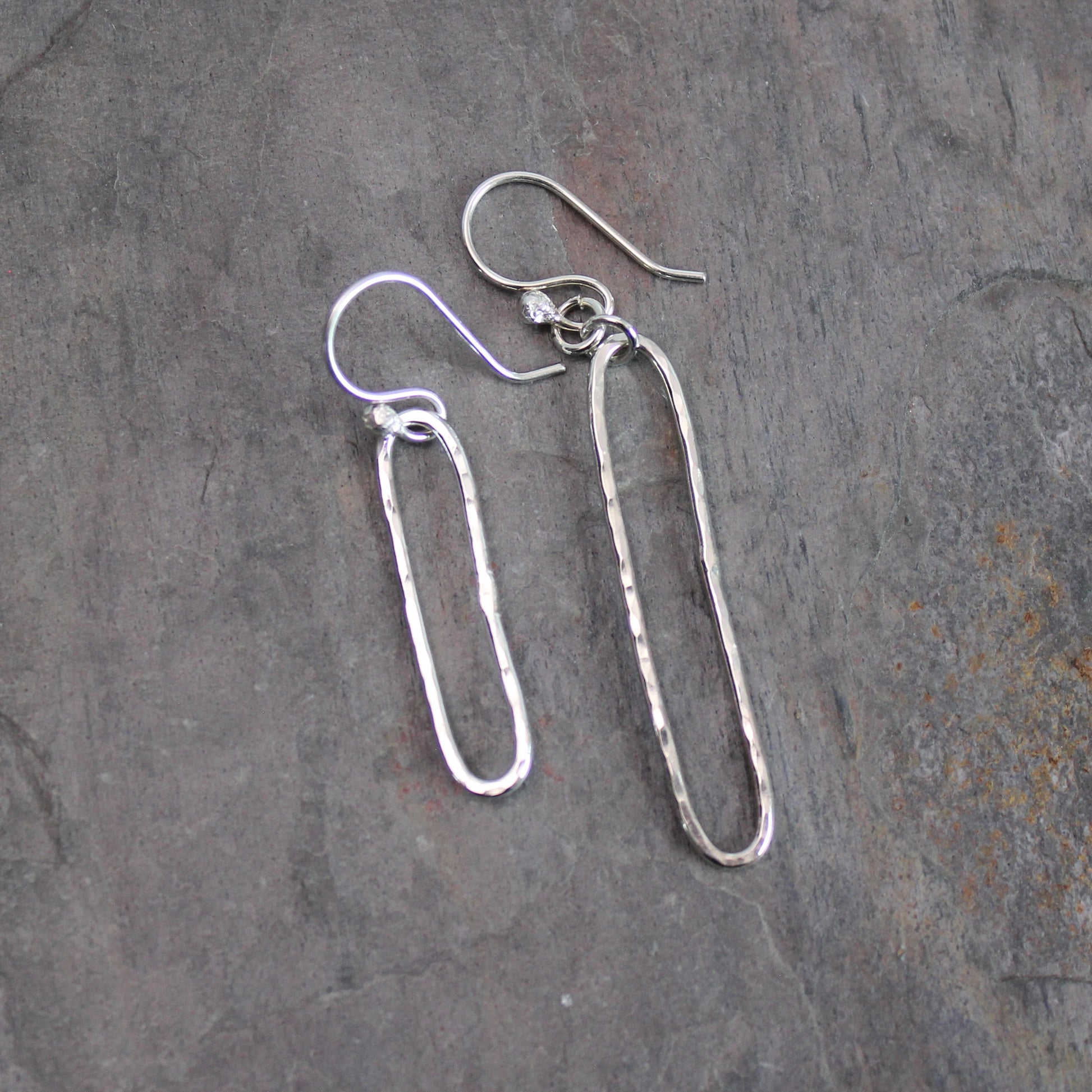 Pair of silver earrings on a textured gray surface