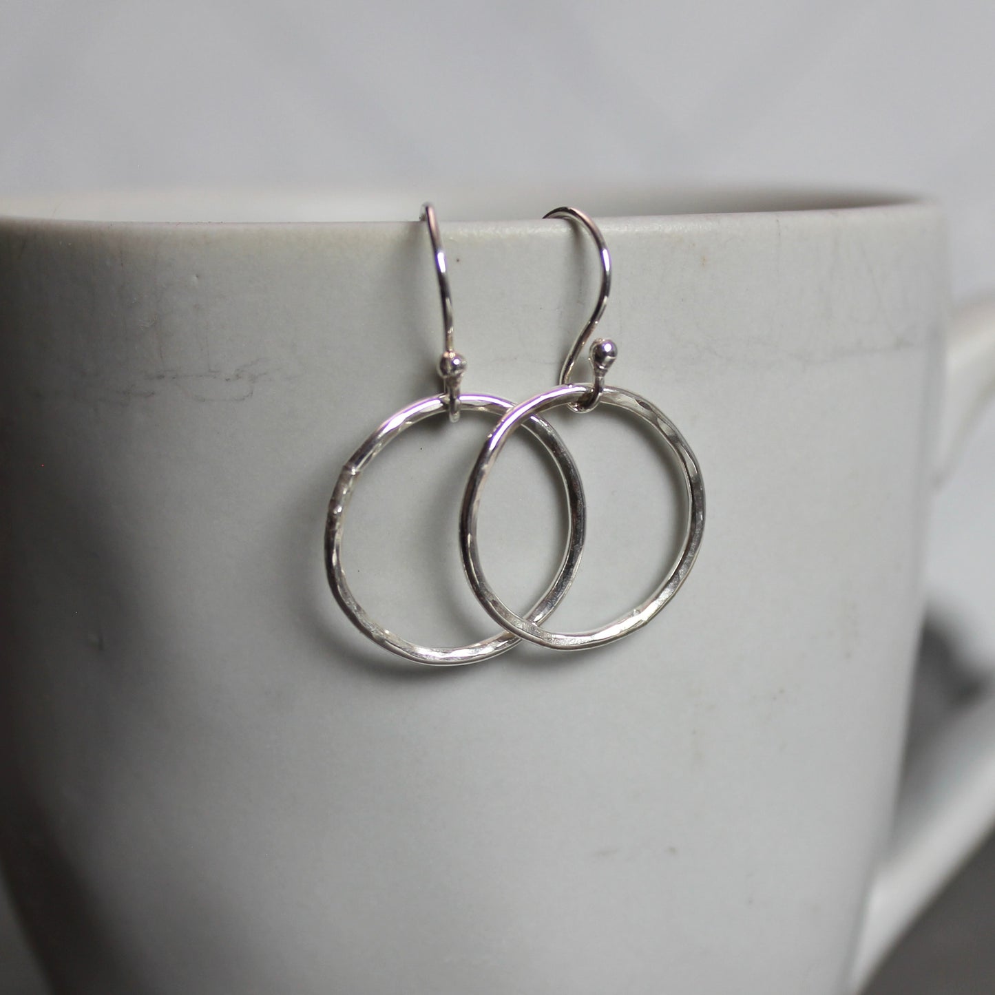 Silver hoop earrings on a white cup