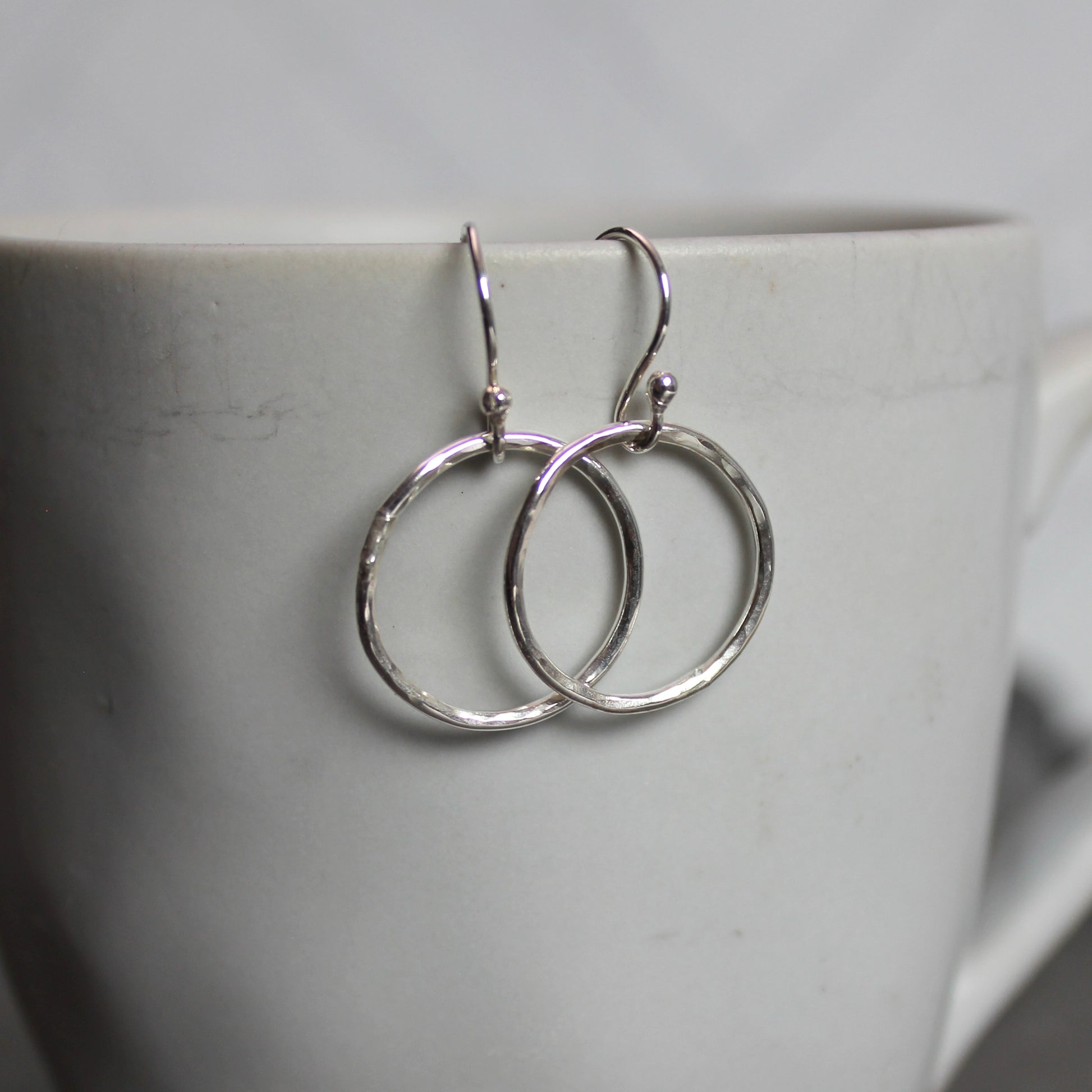 Silver hoop earrings on a white cup