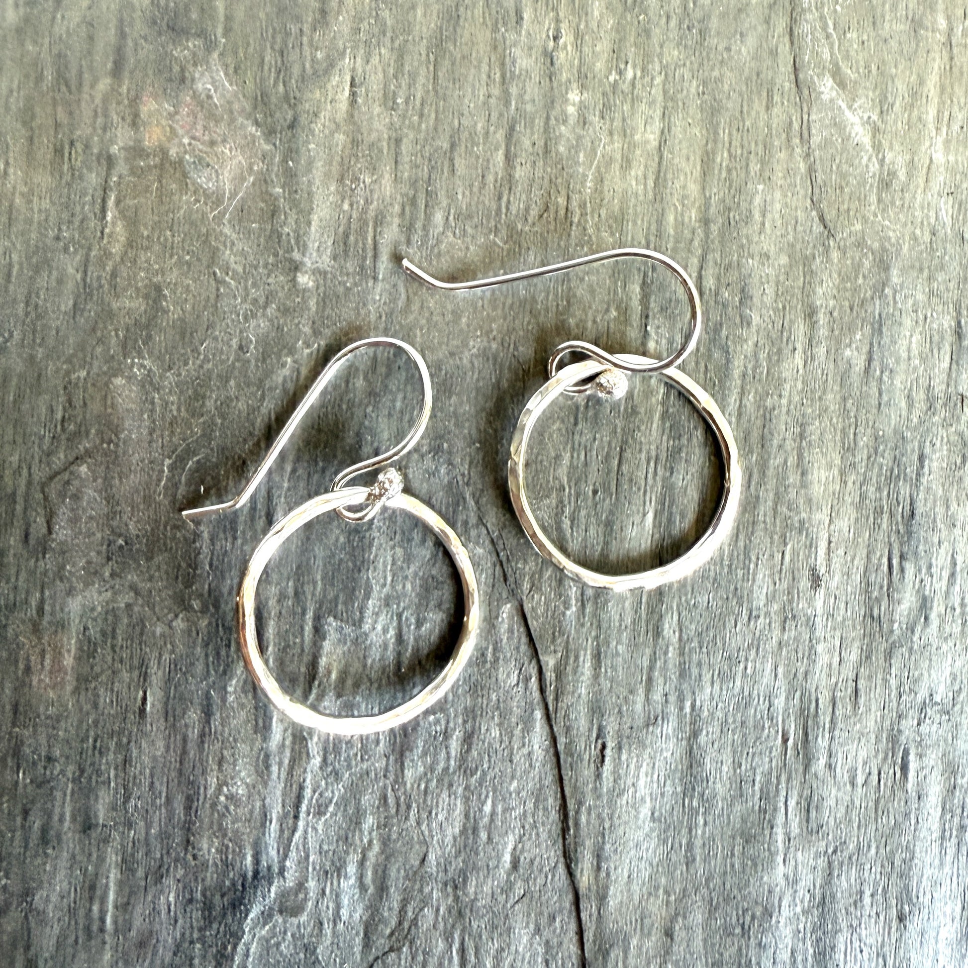 Silver hoop earrings on a gray wooden surface