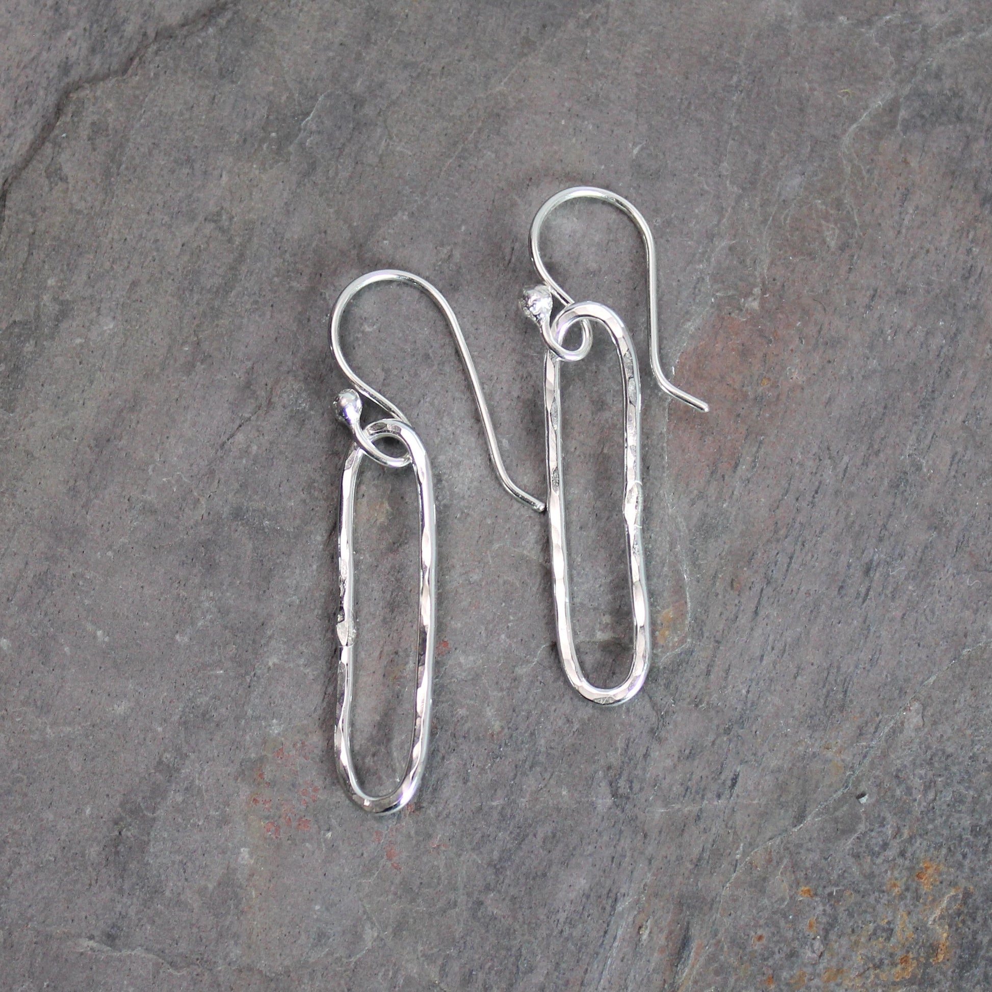 Pair of silver earrings on a gray stone surface
