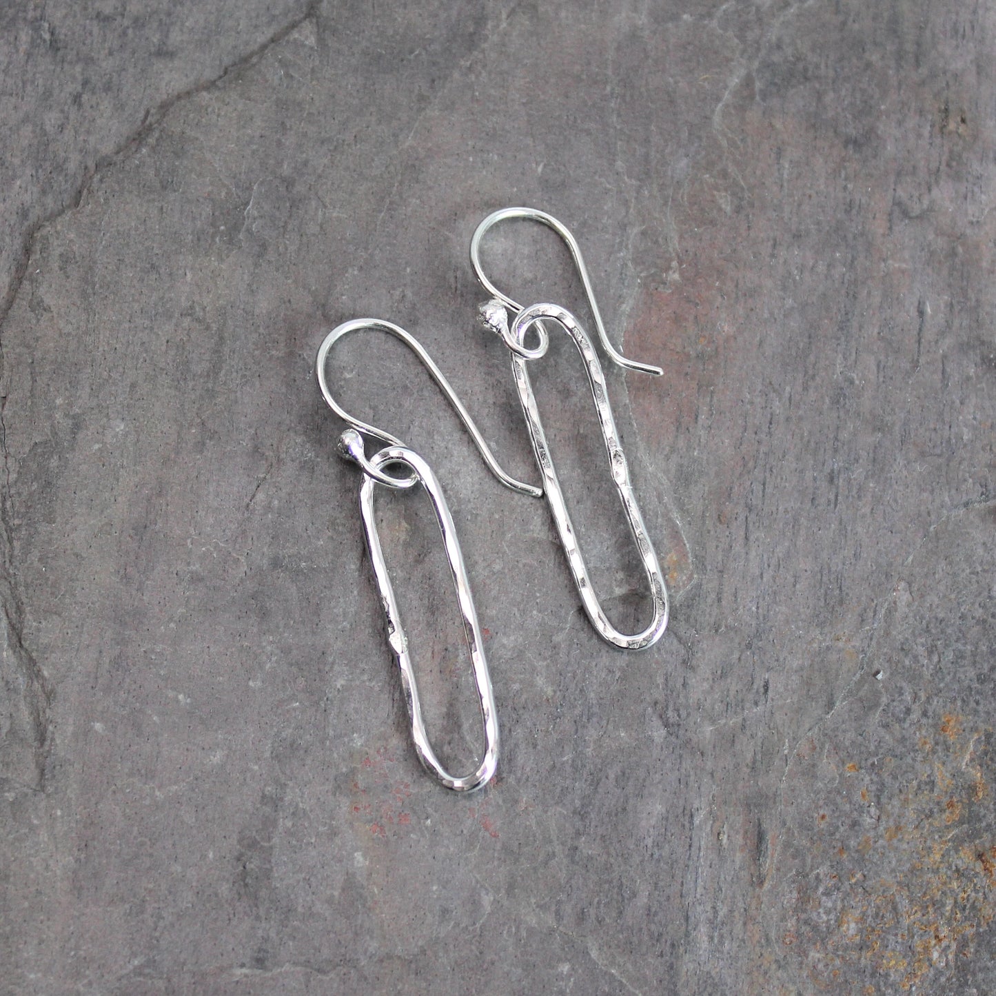 Silver earrings on a textured gray surface