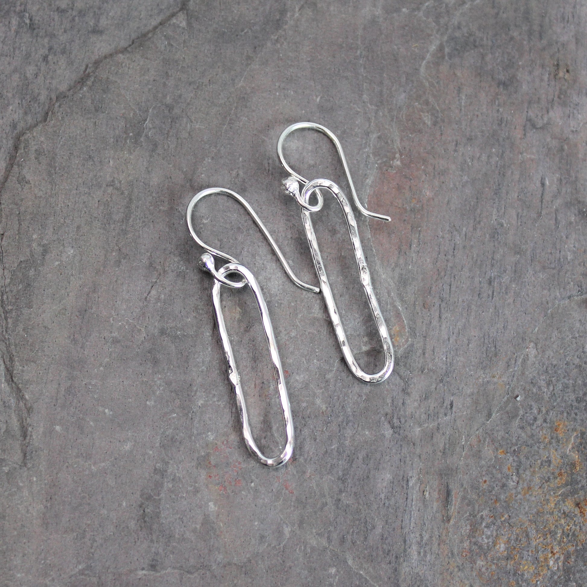 Silver earrings on a textured gray surface