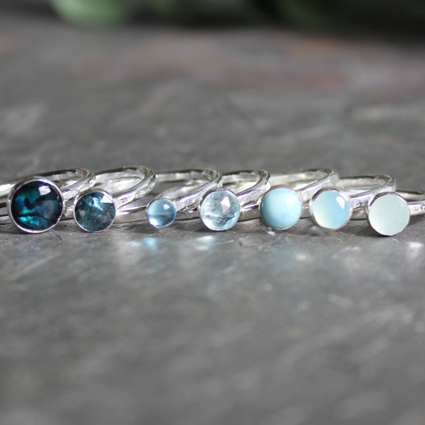 Set of silver rings with blue gemstones on a gray surface
