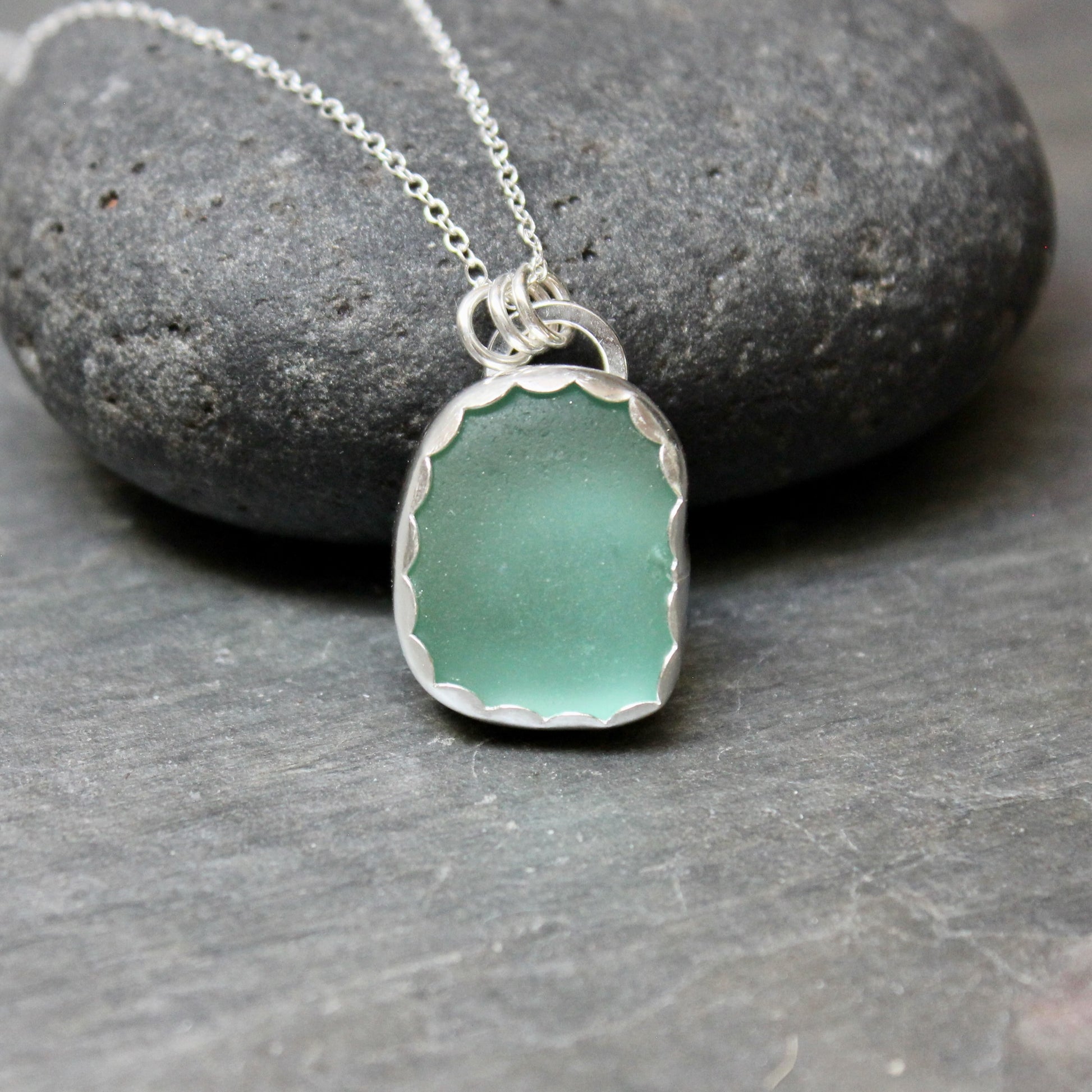 Necklace with a green sea glass pendant on a stone surface