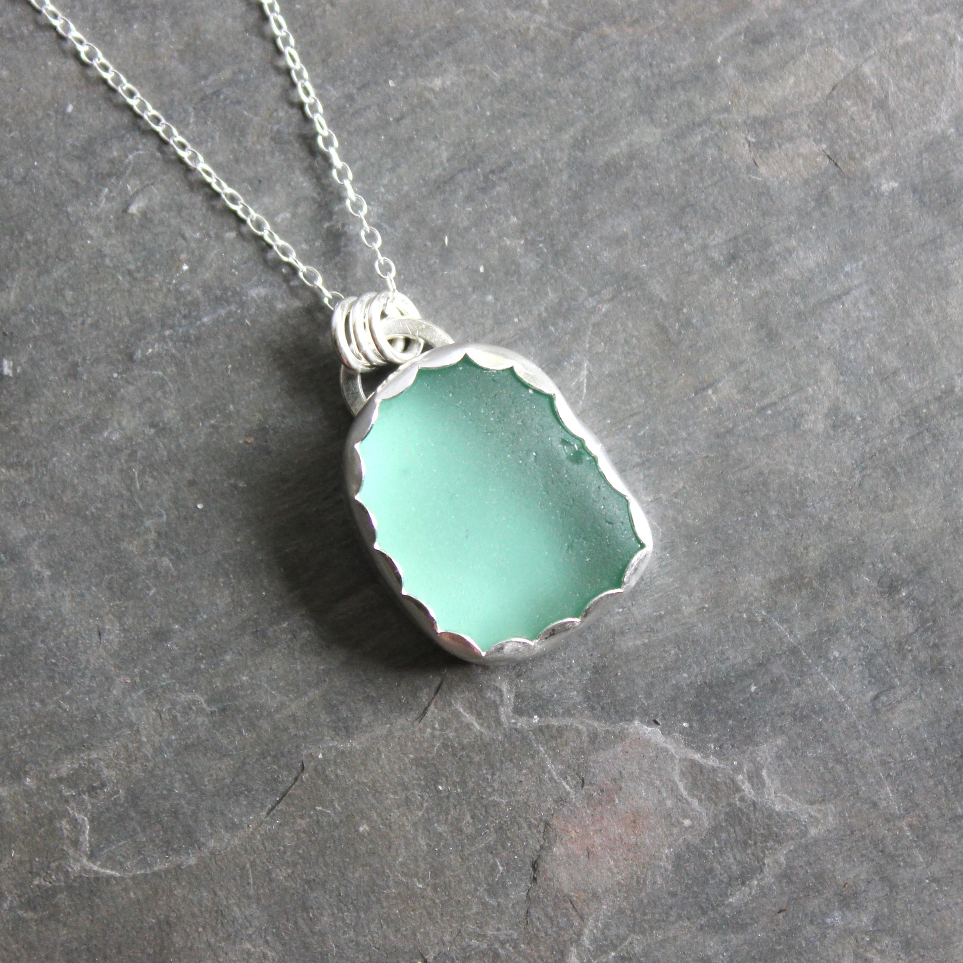 Necklace with a green sea glass on a gray surface