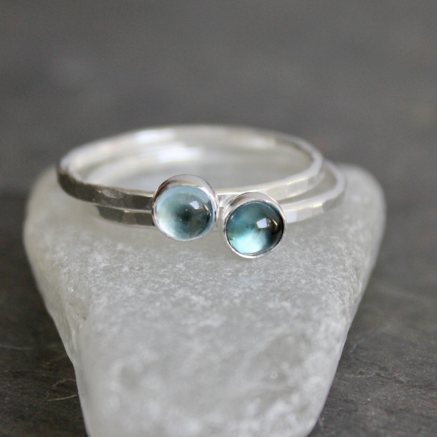 Silver ring with two blue gemstones on a gray stone surface