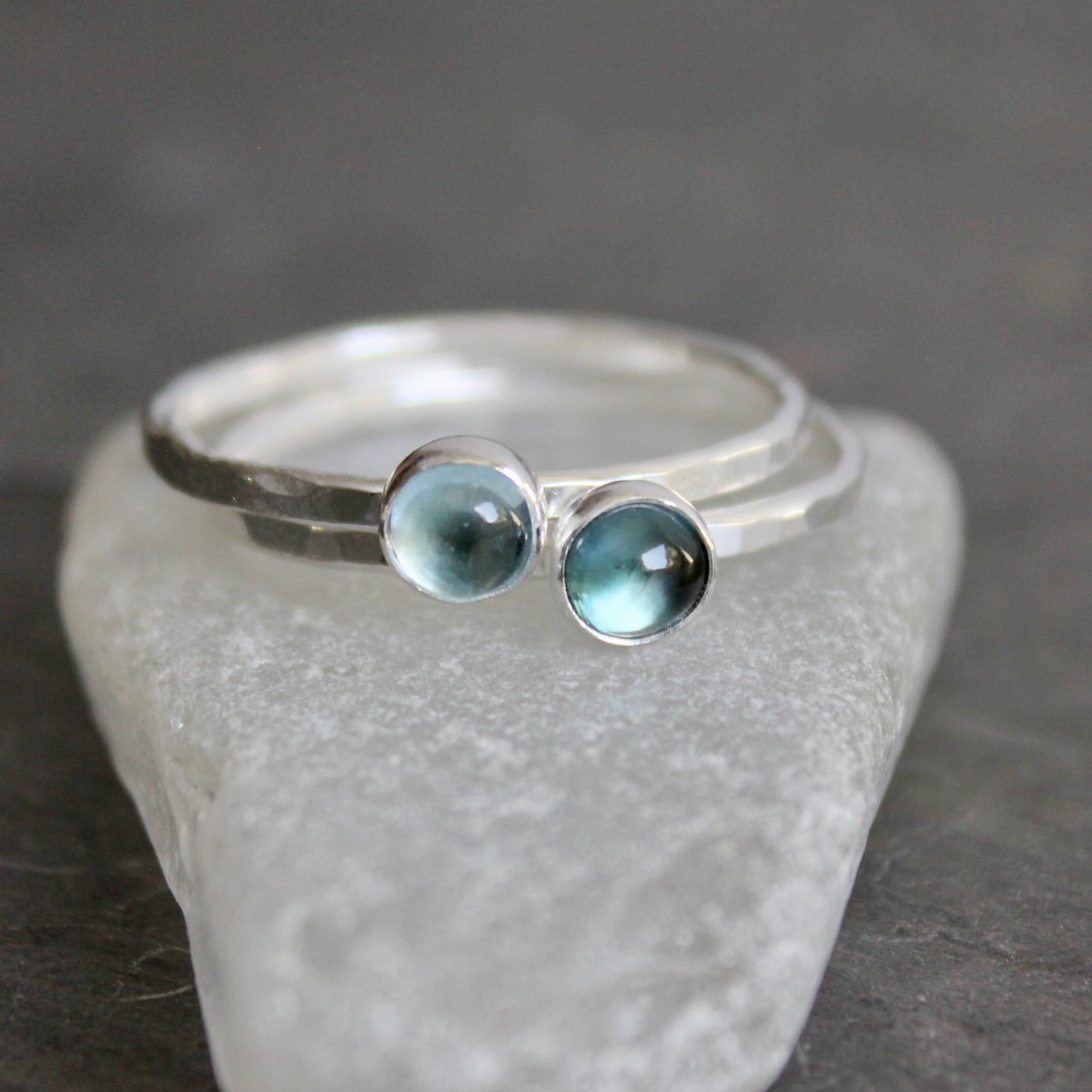 Silver ring with two blue gemstones on a gray stone surface