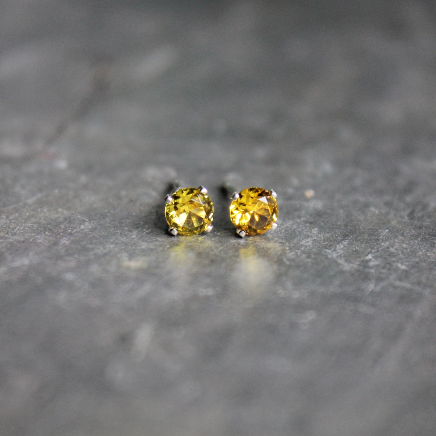 These stud earrings are made with 4mm round faceted lab created golden yellow topaz set in 4-prong sterling silver stud earring settings with earring backs.