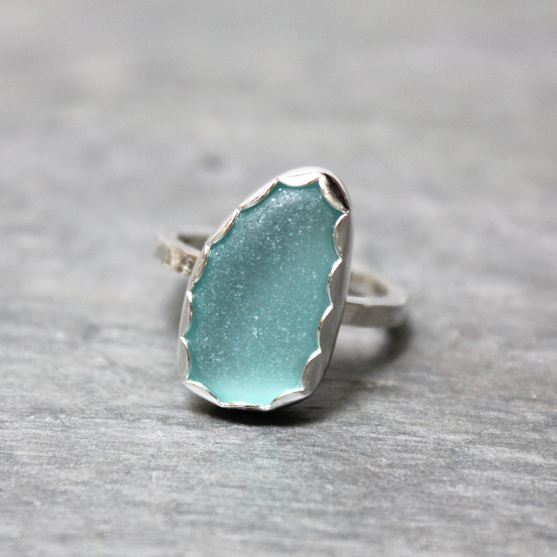 Turquoise sea glass ring with silver band on a gray background