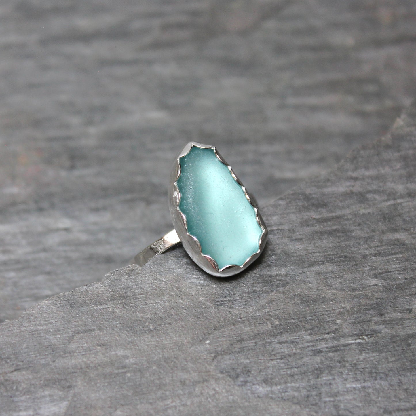 Turquoise sea glass ring with silver band on a gray background