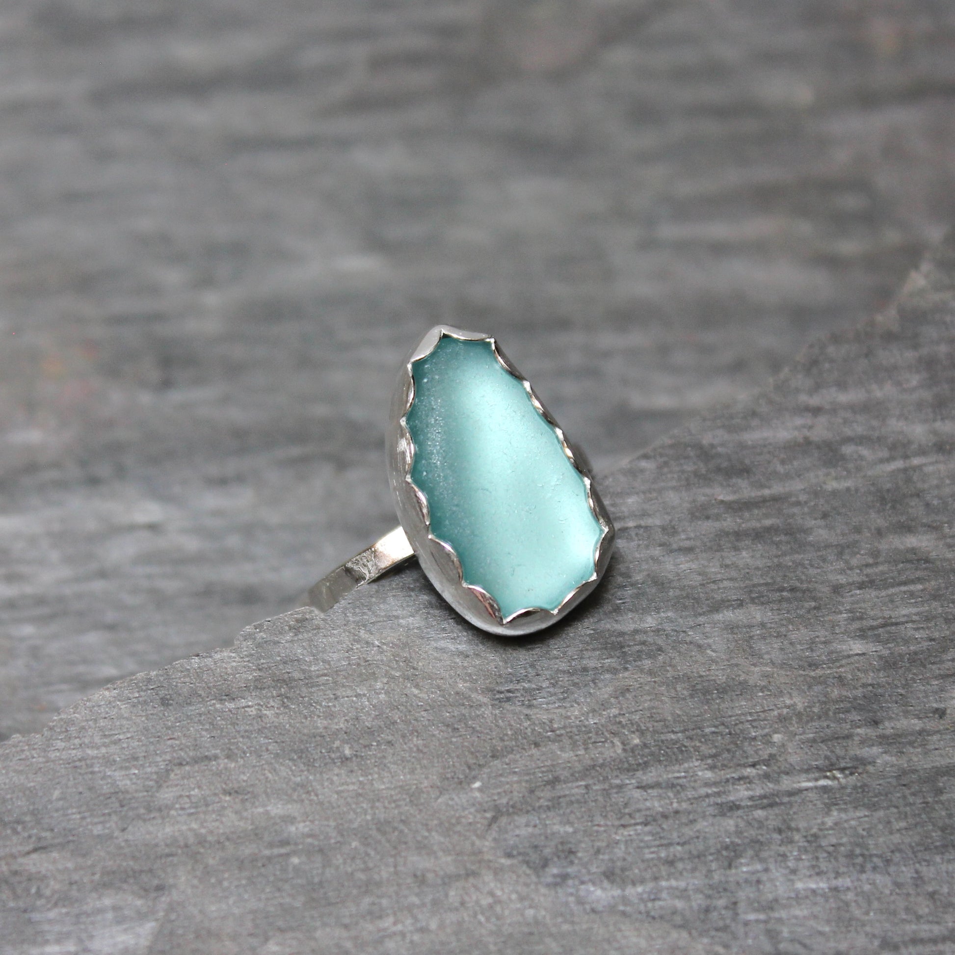 Turquoise sea glass ring with silver band on a gray background
