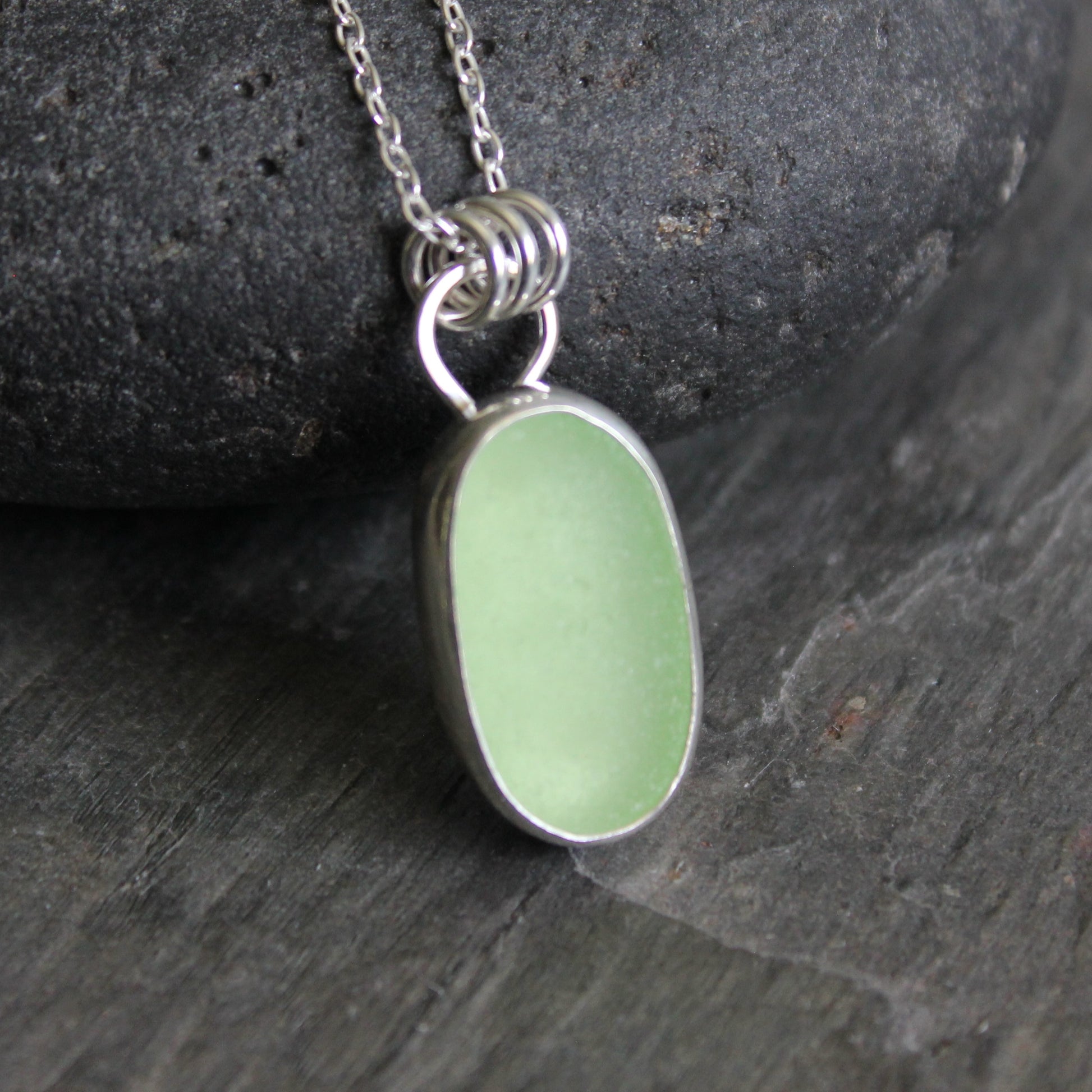 Necklace with a pale-yellow uranium pendant on a gray stone surface