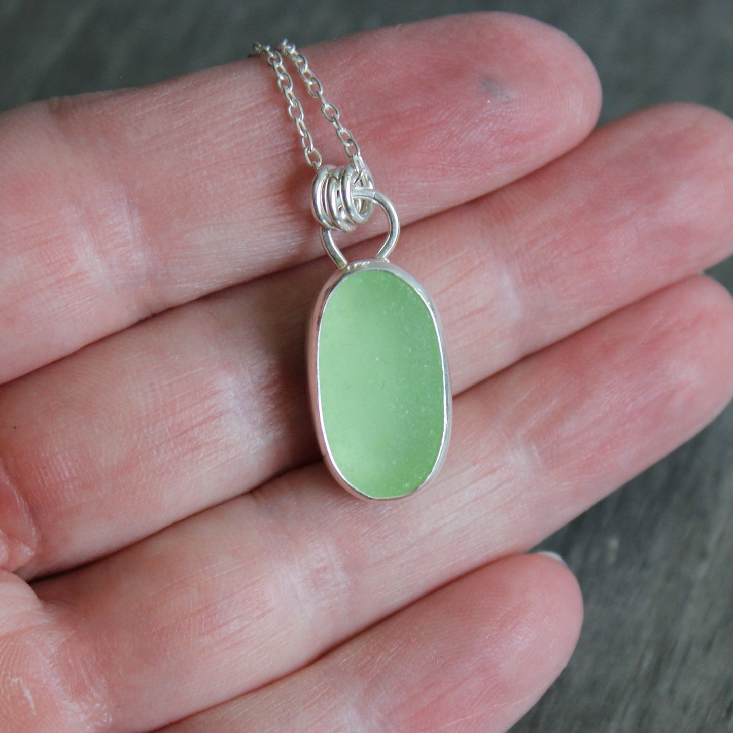 Necklace with a pale-yellow uranium pendant on a hand