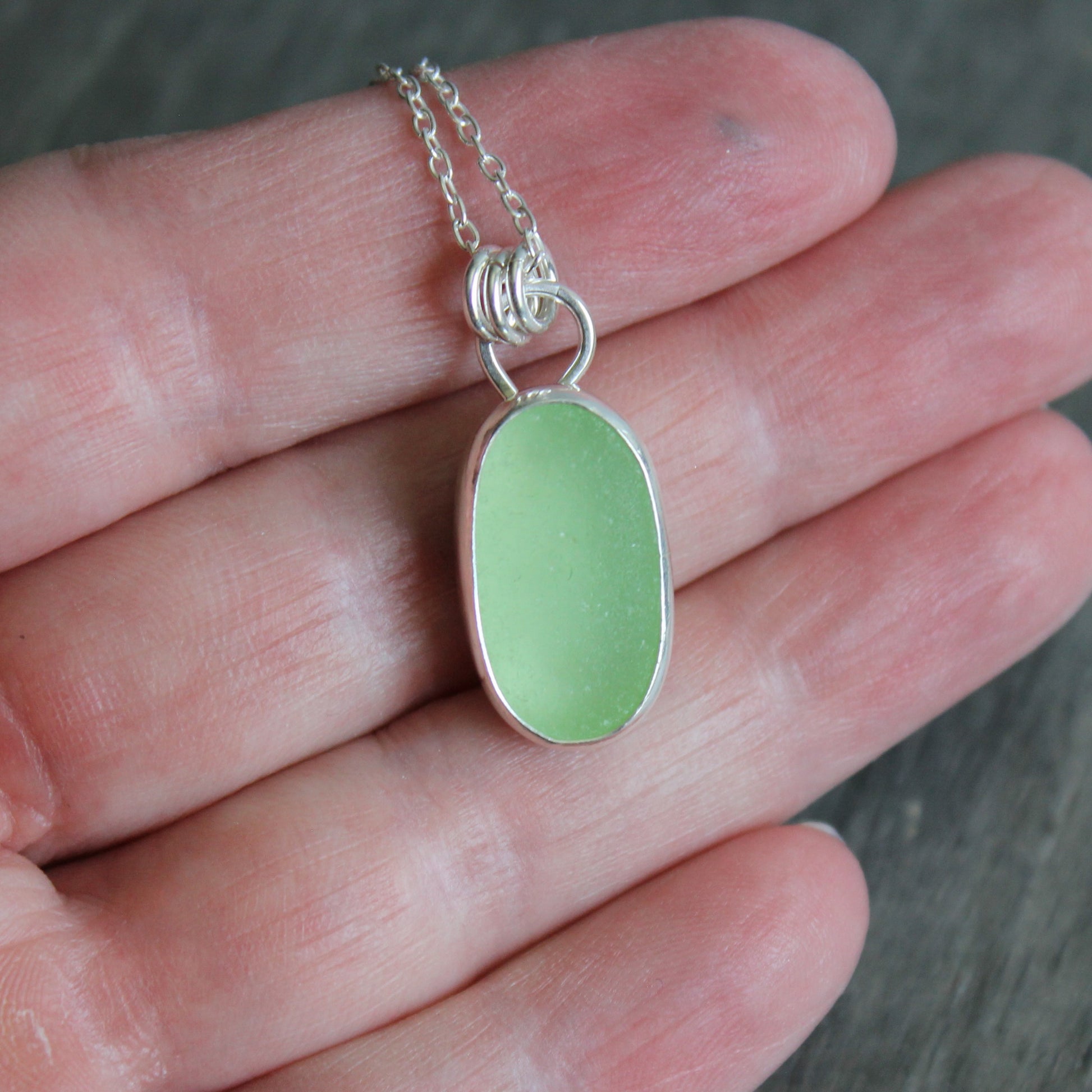 Necklace with a pale-yellow uranium pendant on a hand