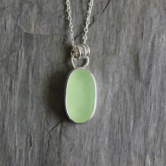 Necklace with a pale-yellow uranium pendant on a gray stone surface