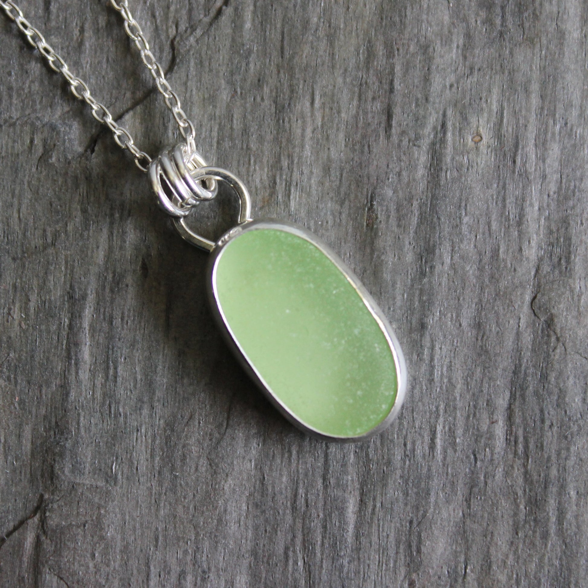 Necklace with a pale-yellow uranium pendant on a gray stone surface