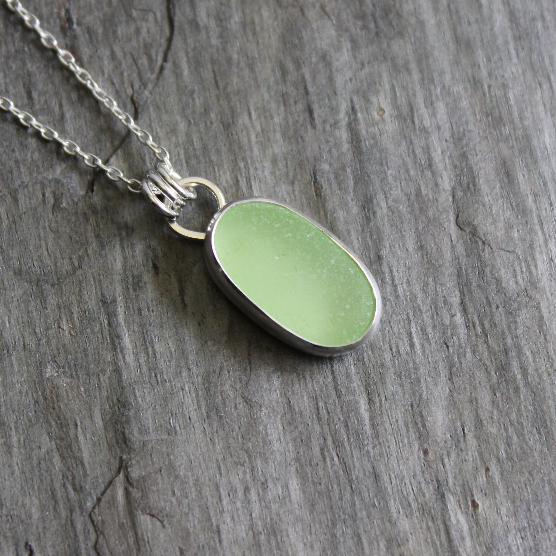Necklace with a pale-yellow uranium pendant on a gray stone surface